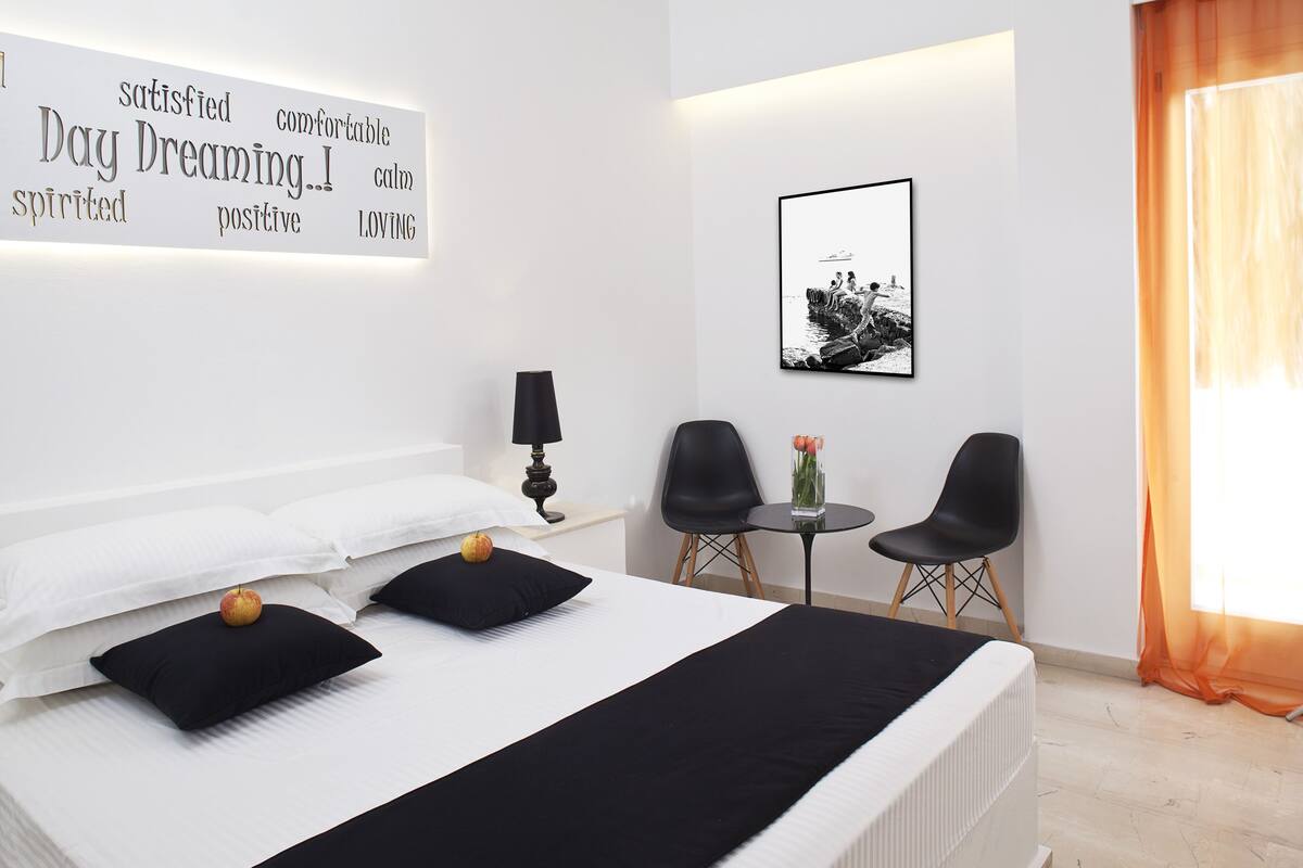 Une chambre d’hôtel moderne avec un lit bien fait, une petite table avec des chaises et un tableau encadré au mur.