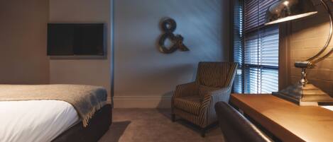 A bedroom with a bed, a chair, a desk, and a lamp.