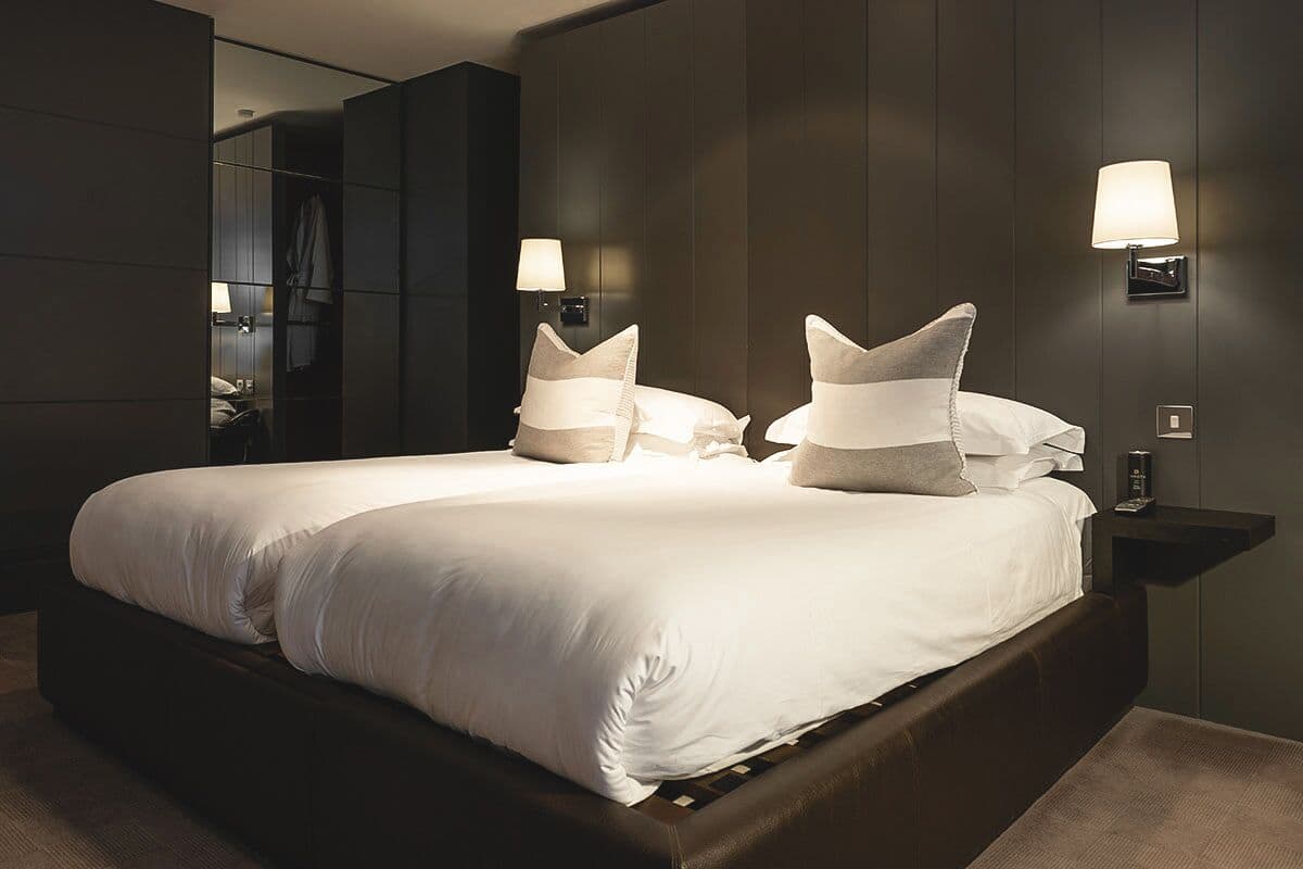 Une chambre d’hôtel moderne avec un grand lit, deux lampes de chevet et un miroir.