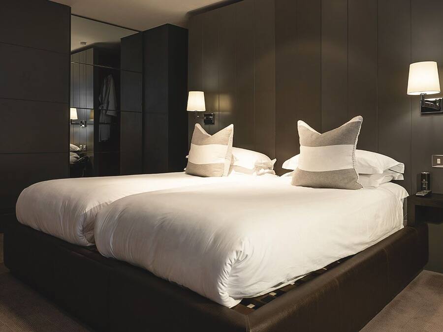 Ein modernes Hotelzimmer mit einem großen Bett, zwei Nachttischlampen und einem Spiegel.