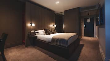 Una habitación de hotel moderna con una cama grande, mesitas de noche, un escritorio y una silla.