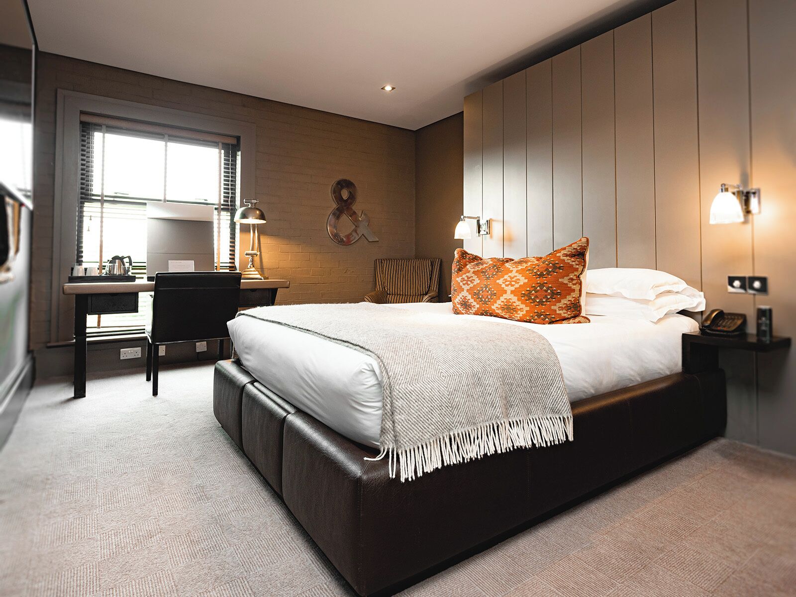A modern hotel room with a large bed, a desk, and a chair.