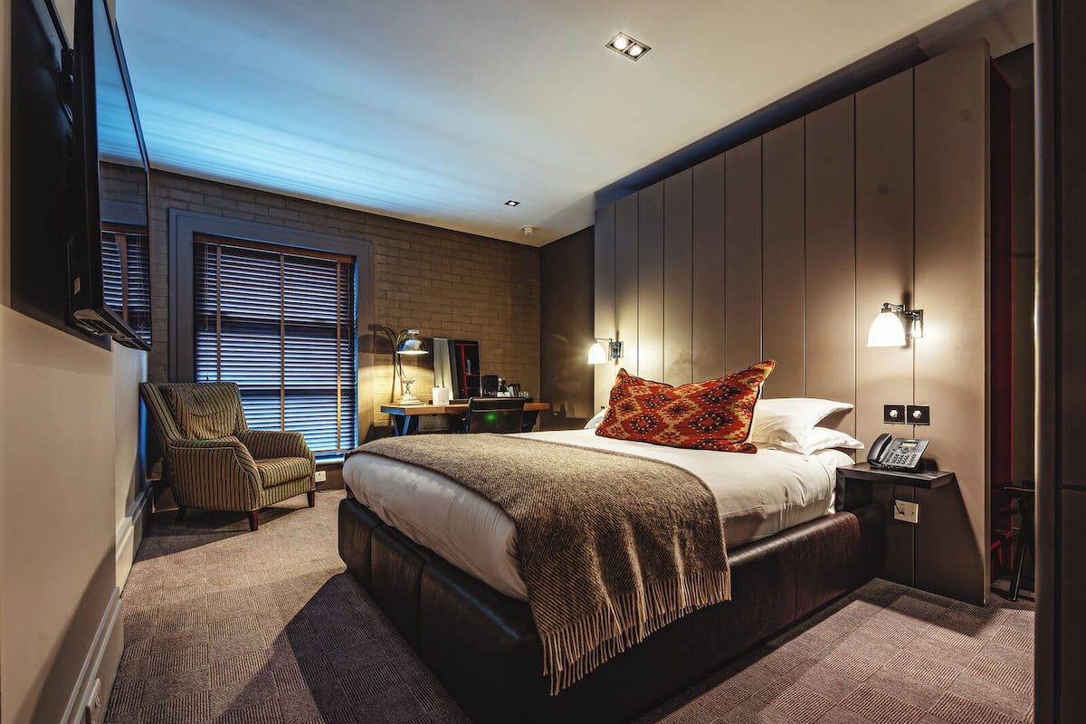 Une chambre d’hôtel moderne équipée d’un grand lit, d’un bureau, d’une chaise et d’un téléviseur.