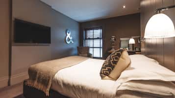 Un dormitorio moderno con una cama grande, un televisor montado en la pared, una ventana con persianas y una lámpara de pared original.