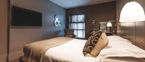Une chambre moderne avec un grand lit, un téléviseur fixé au mur, une fenêtre avec des stores et un luminaire mural original.