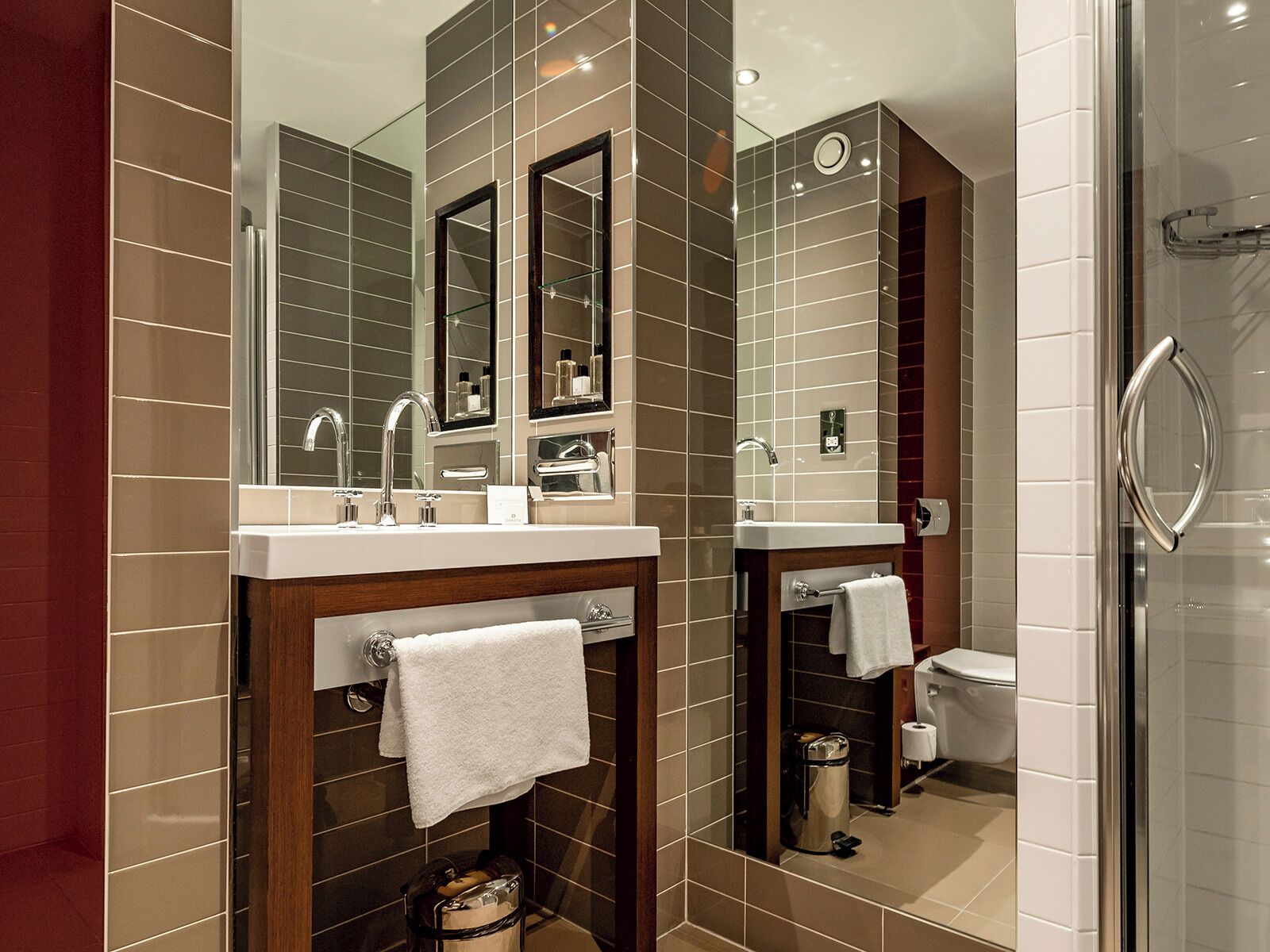 A modern bathroom with two sinks, a large mirror, and a glass shower enclosure.