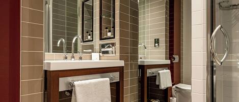 Un baño moderno con dos lavamanos, un espejo grande y una cabina de ducha de vidrio.