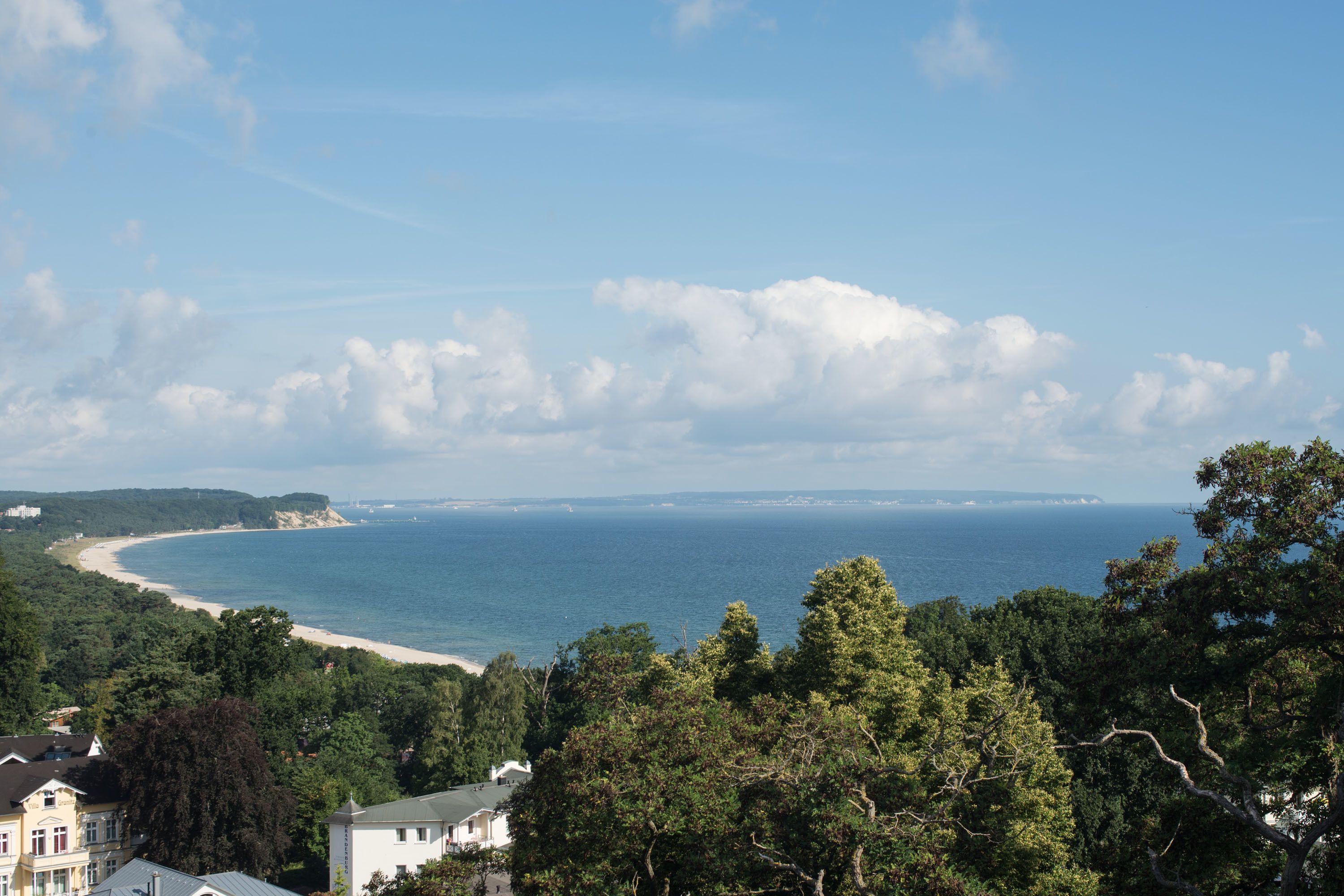 Un paisaje costero con playa, zona boscosa y vista al mar.