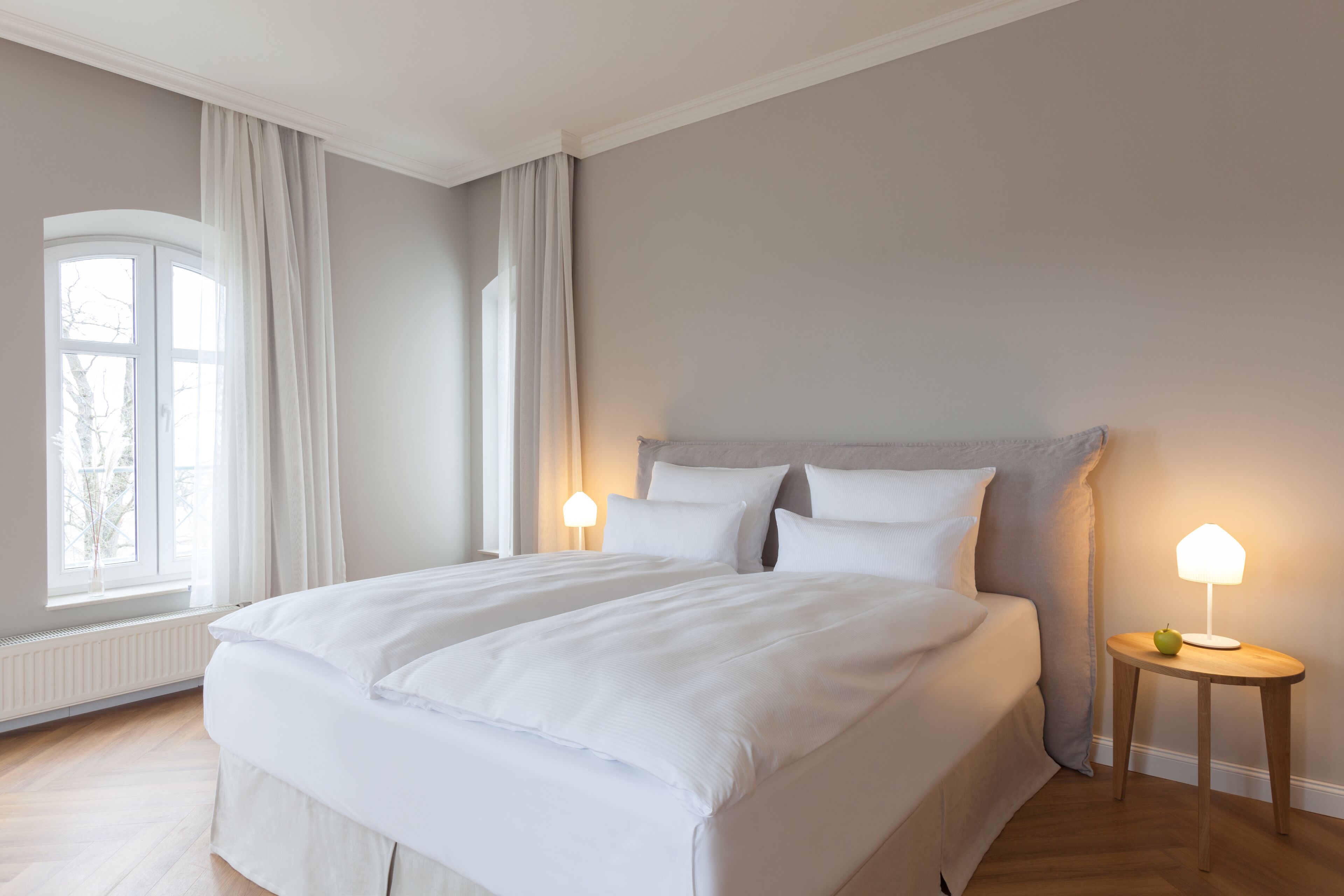 A bedroom with a large bed, two bedside tables, and a window with curtains.