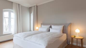 A bedroom with a large bed, two bedside tables, and a window with curtains.