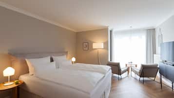 Habitación de hotel con una cama grande, dos lámparas de noche, un escritorio con silla, un televisor y una ventana con cortinas.