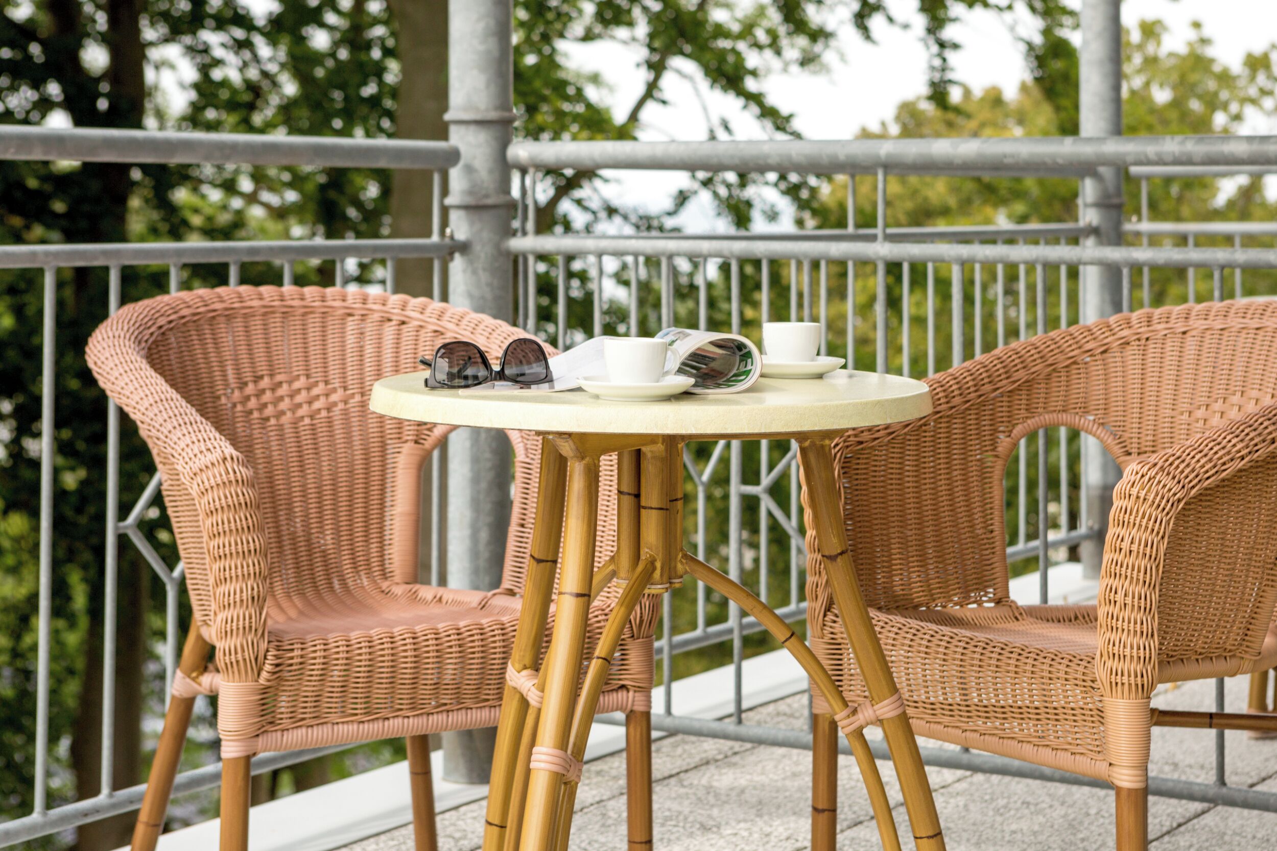 A wicker table with two chairs on a balcony.