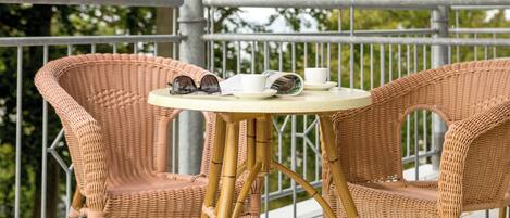 Een rieten tafel met twee stoelen op een balkon.