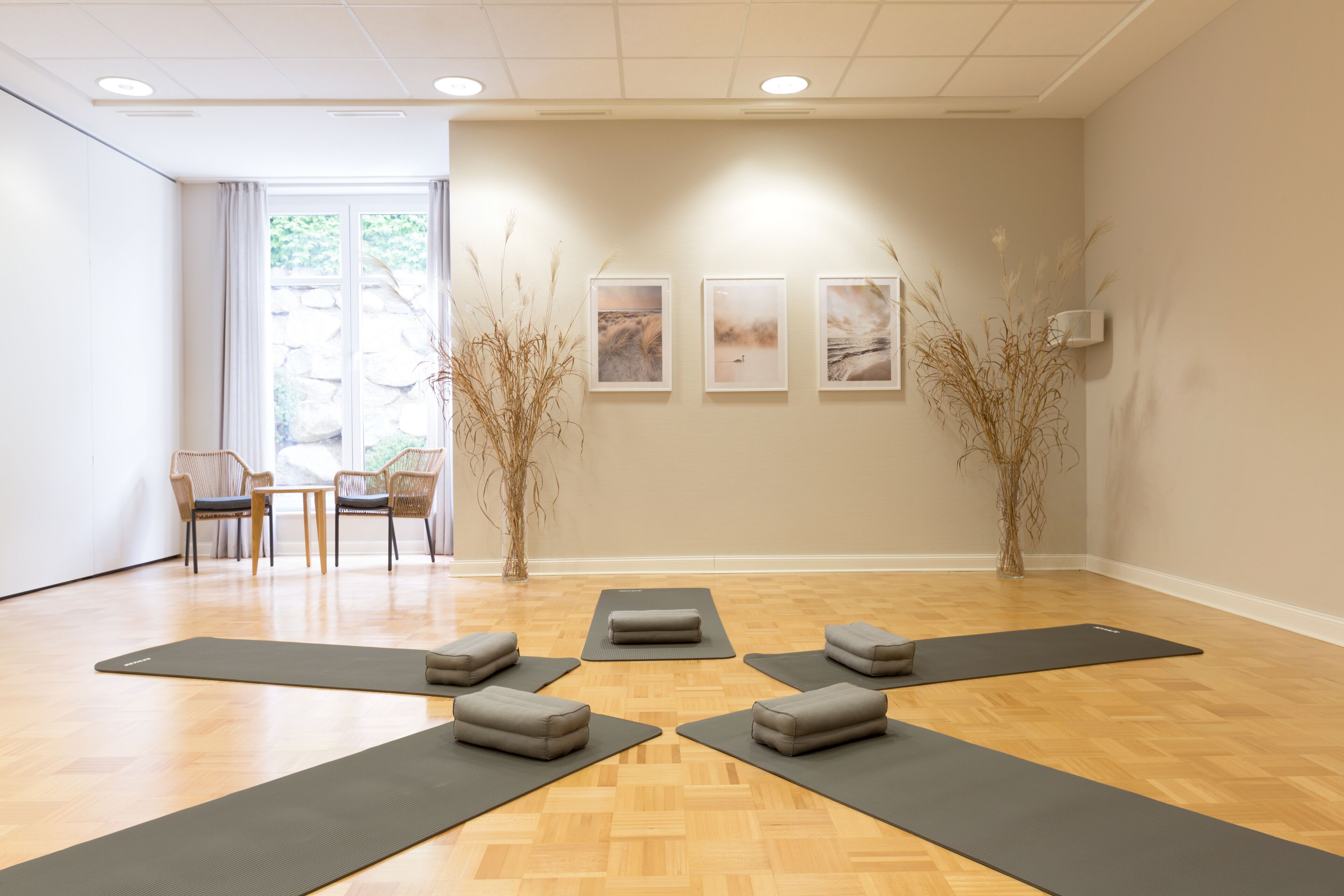 A yoga studio with wooden flooring, multiple yoga mats, and chairs.