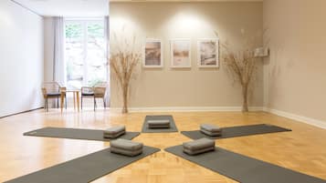 A yoga studio with wooden flooring, multiple yoga mats, and chairs.