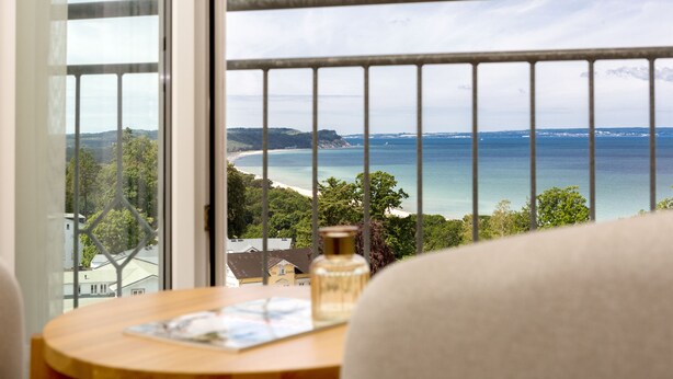 A room with a view of a beach and ocean through a barred window. - Vju Hotel Rügen (Göhren)