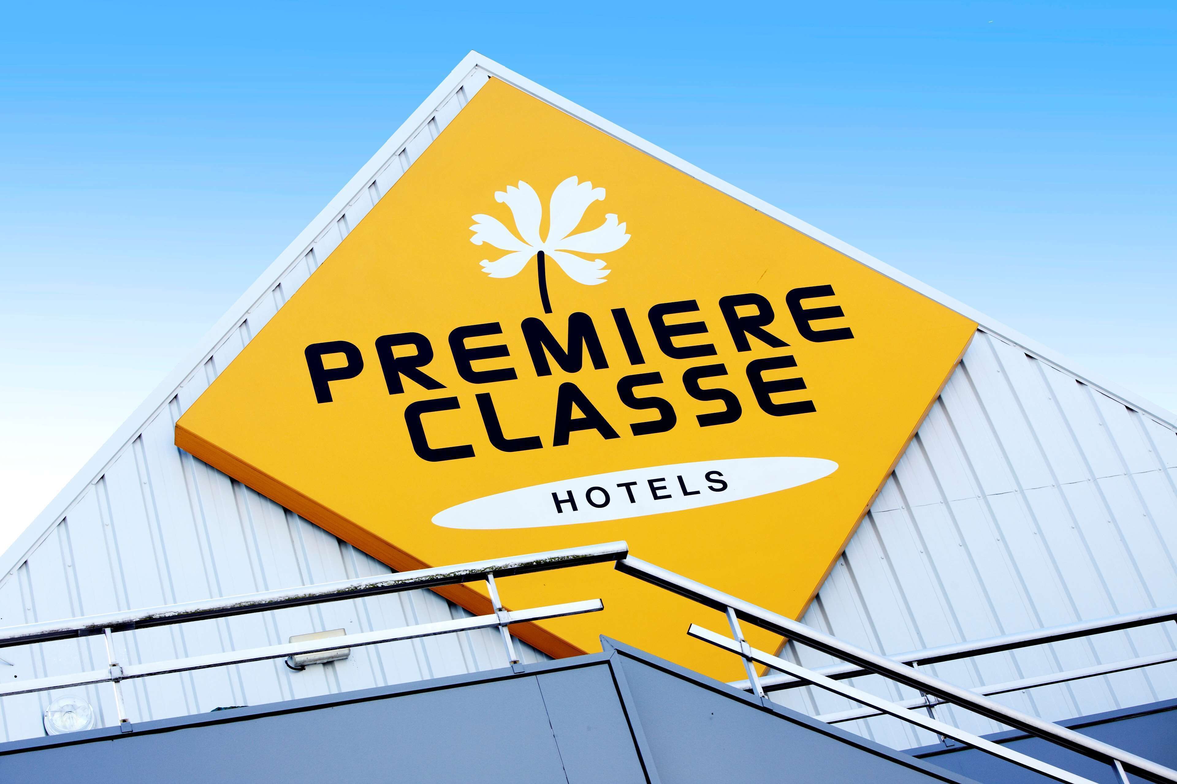 En gul skylt med texten ”Premiere Classe Hotels” och en logotyp som föreställer ett lönnblad.