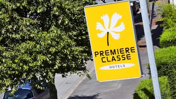 A yellow sign with a white fleur-de-lis symbol and the text "PREMIERE CLASSE HOTELS".