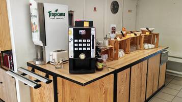 Una estación de café autoservicio con un dispensador de Tropicana Pure Premium, una máquina de café y un tostador.