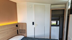 Une chambre avec un lit, une armoire et un petit coin cuisine.
