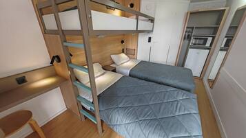 A compact room with a bunk bed, a desk, and a kitchenette.