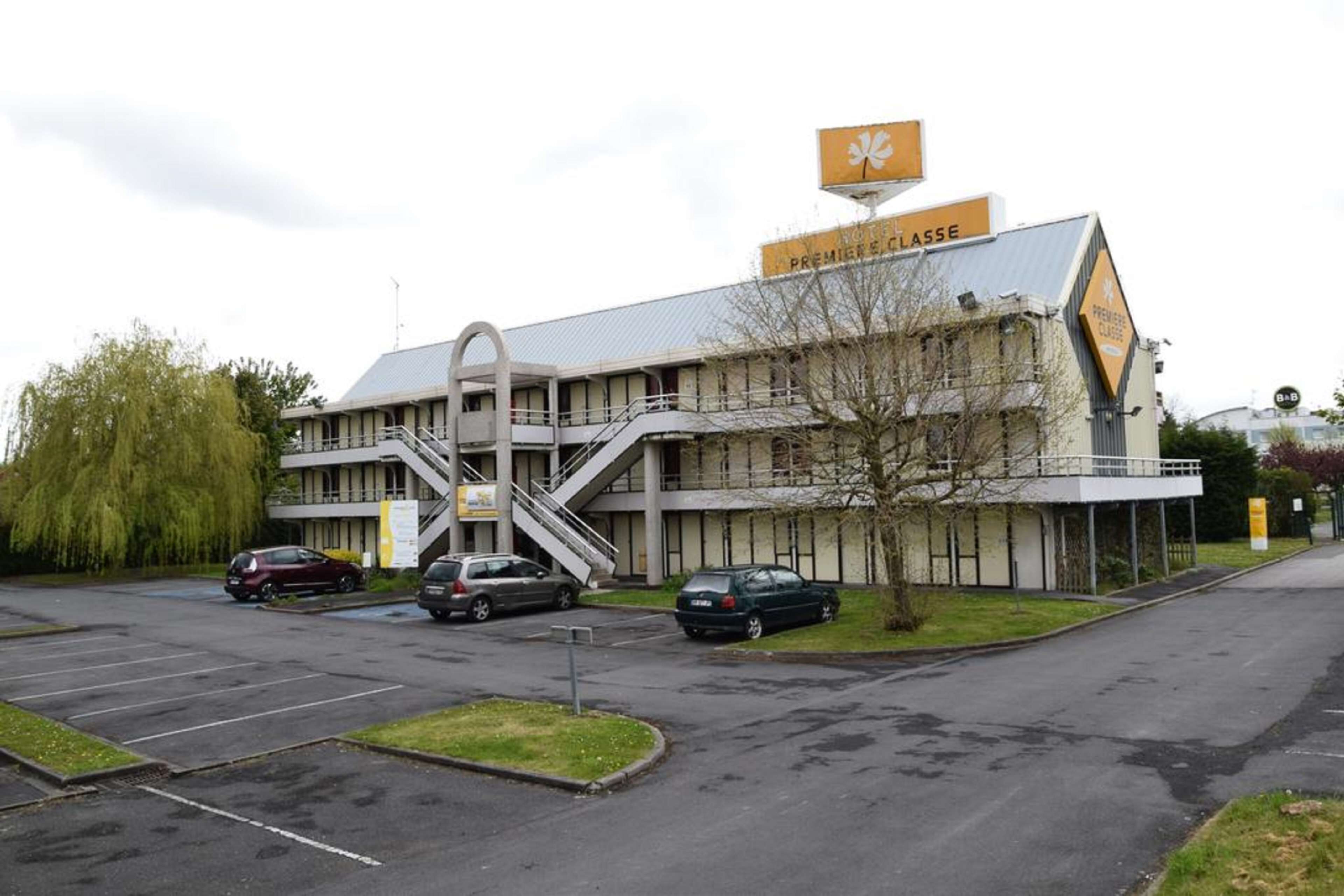 A building with a sign reading "PREMIERE CLASSE" and a staircase leading to the entrance.