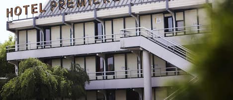 A hotel named "HOTEL PREMIERE CLASSE" with a modern architectural design, featuring a prominent balcony and a staircase leading to the entrance.