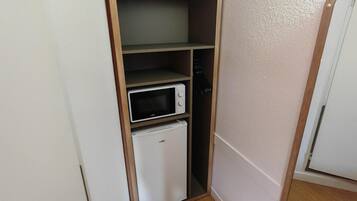 Een kleine keuken met een magnetron en een minibar.