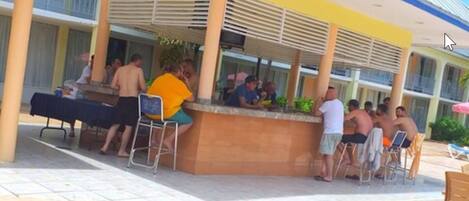 Zona de bar al aire libre con mostrador y asientos.