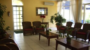 Eine Lobby mit Korbsesseln, einem Holztisch und Zimmerpflanzen.