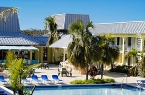 A hotel with a swimming pool, lounge chairs, and palm trees. - Royal Islander Hotel (Freeport)