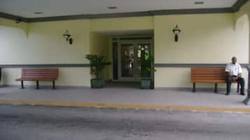 A building entrance with two benches, potted plants, and a door.