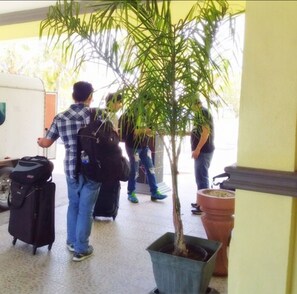 A group of people with luggage at a doorway, a potted plant, and a tiled floor. - Royal Islander Hotel (Freeport)