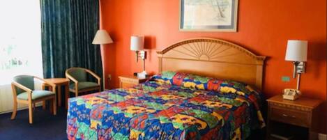 A hotel room with a large bed, two bedside tables with lamps, a chair, and a window with curtains.