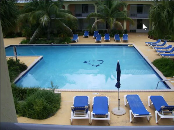 A swimming pool with blue lounge chairs and palm trees. - Royal Islander Hotel (Freeport)