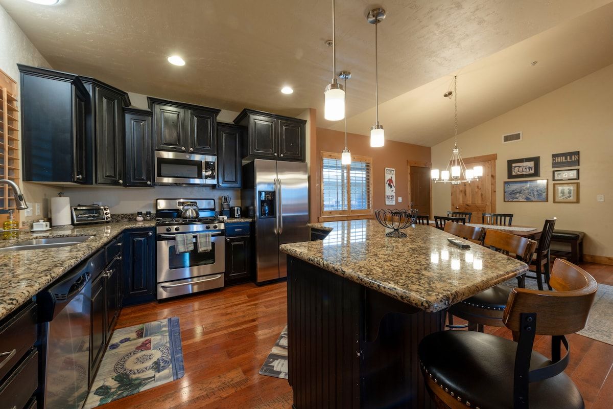 A modern kitchen with dark cabinetry, stainless steel appliances, and a central island.