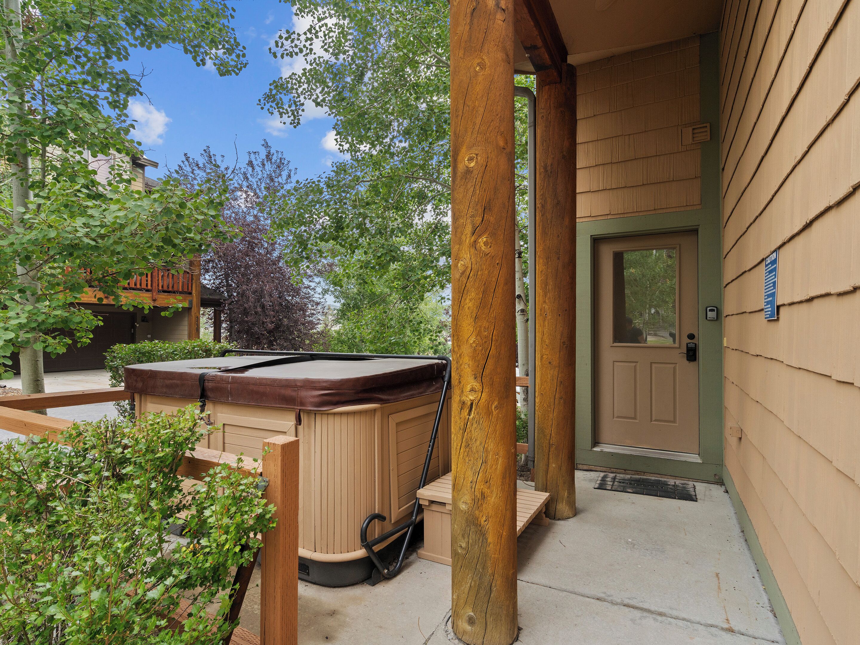 Un bain à remous à l’extérieur d’un bâtiment, avec une terrasse en bois, une porte et une enseigne sur le mur.