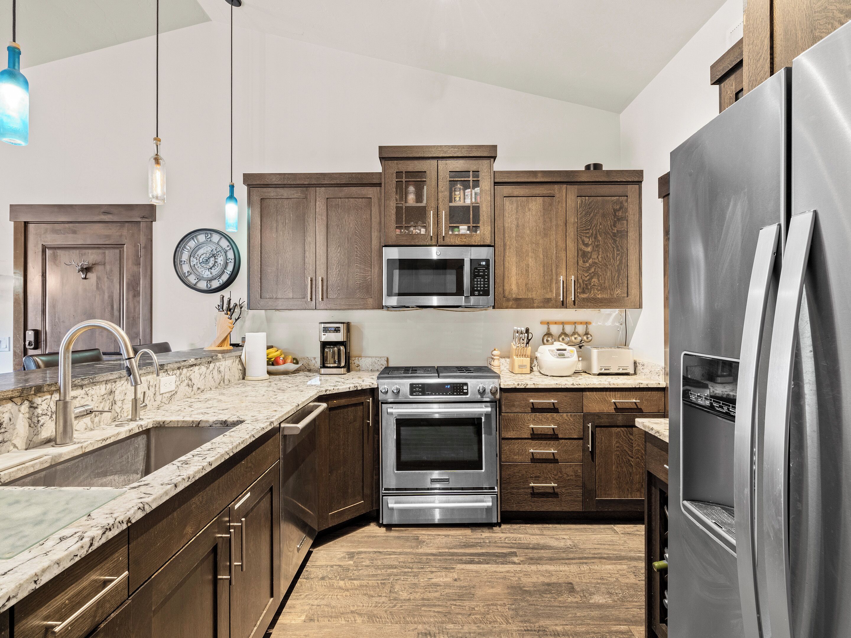 A modern kitchen with dark wooden cabinets, stainless steel appliances, and a marble countertop.