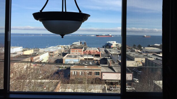 A view from a window overlooking a coastal industrial area with ships in the distance.