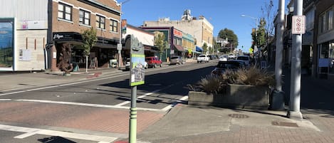 Une vue de rue avec un passage piéton, des panneaux de signalisation et des devantures de magasins.