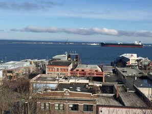 A coastal town with industrial buildings and a large cargo ship in the background.