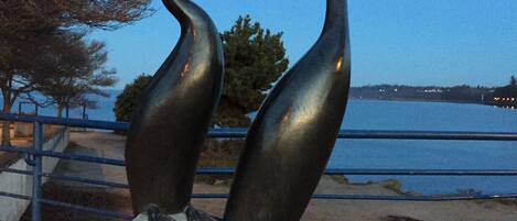 A sculpture of two birds on a rock by a waterfront.