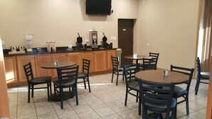 A kitchen with wooden cabinets, a coffee machine, and a TV mounted above the counter. - Port Angeles Inn (Port Angeles)
