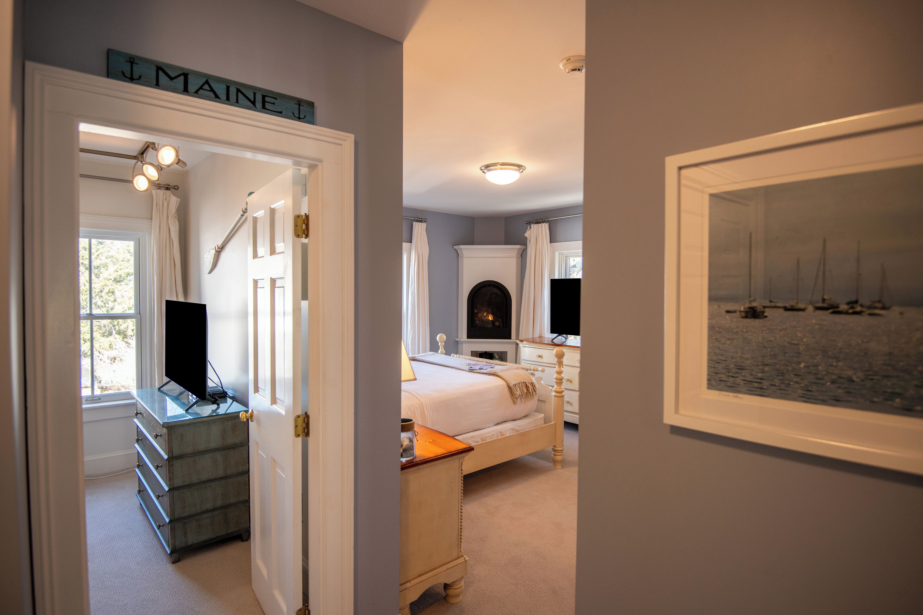 A bedroom with a bed, a dresser, a television, and a framed picture of boats on the wall.