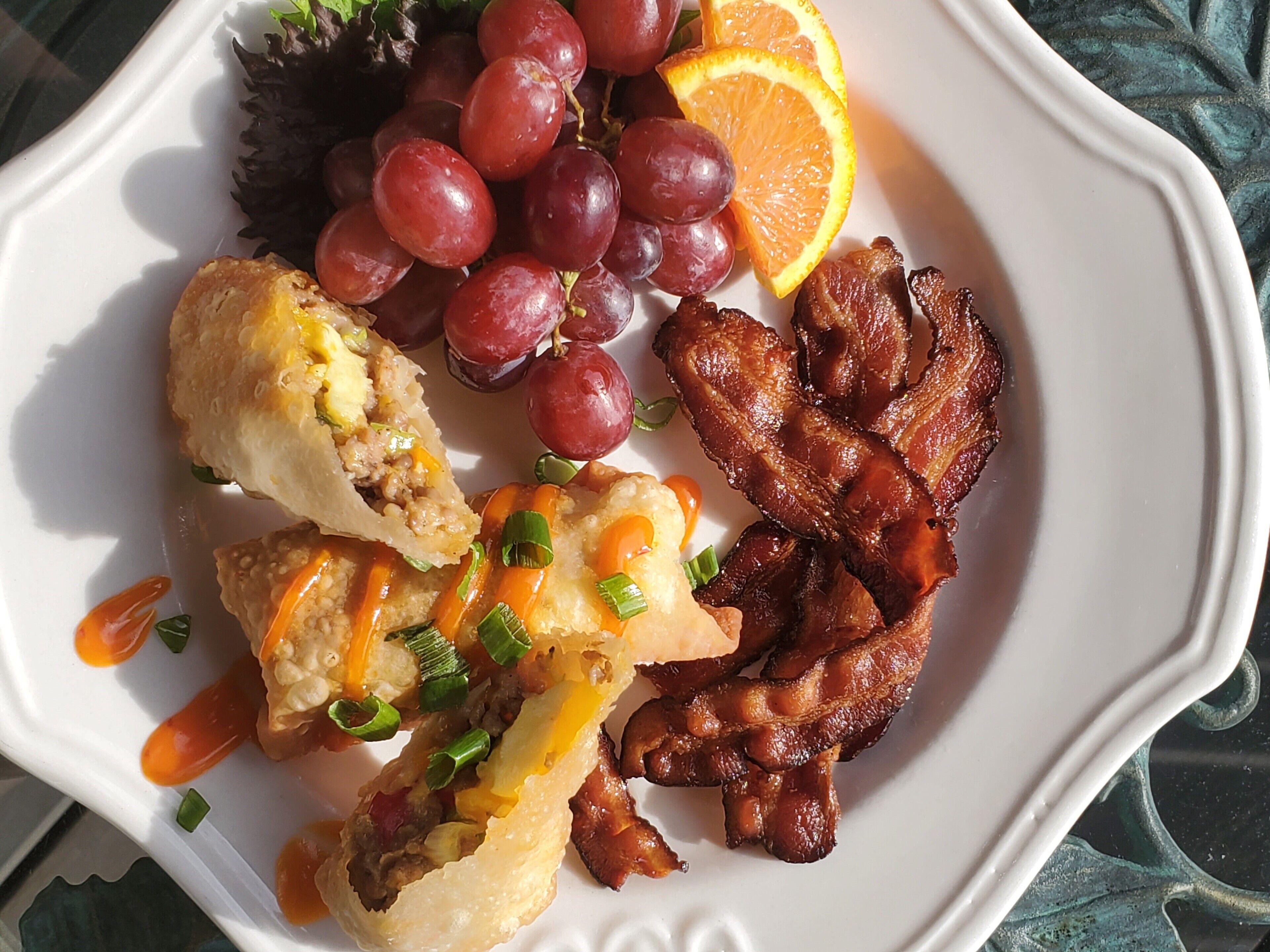 A plate with bacon, eggs, and a salad.