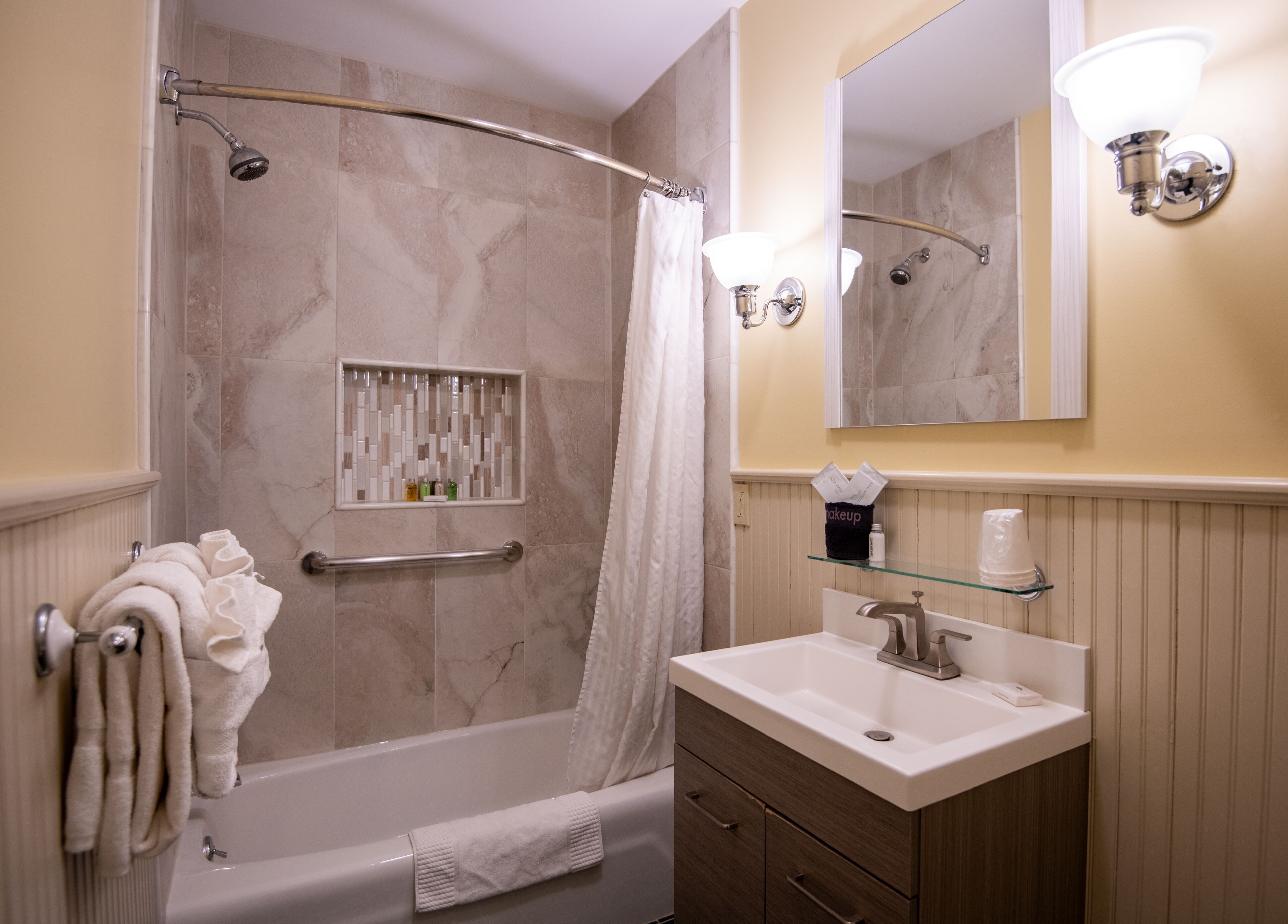Une salle de bain moderne équipée d’une baignoire, d’une douche, d’un meuble-lavabo et d’un miroir.