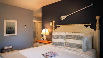 A neatly made bed with a magazine, a bedside lamp, and a framed picture on the wall.
