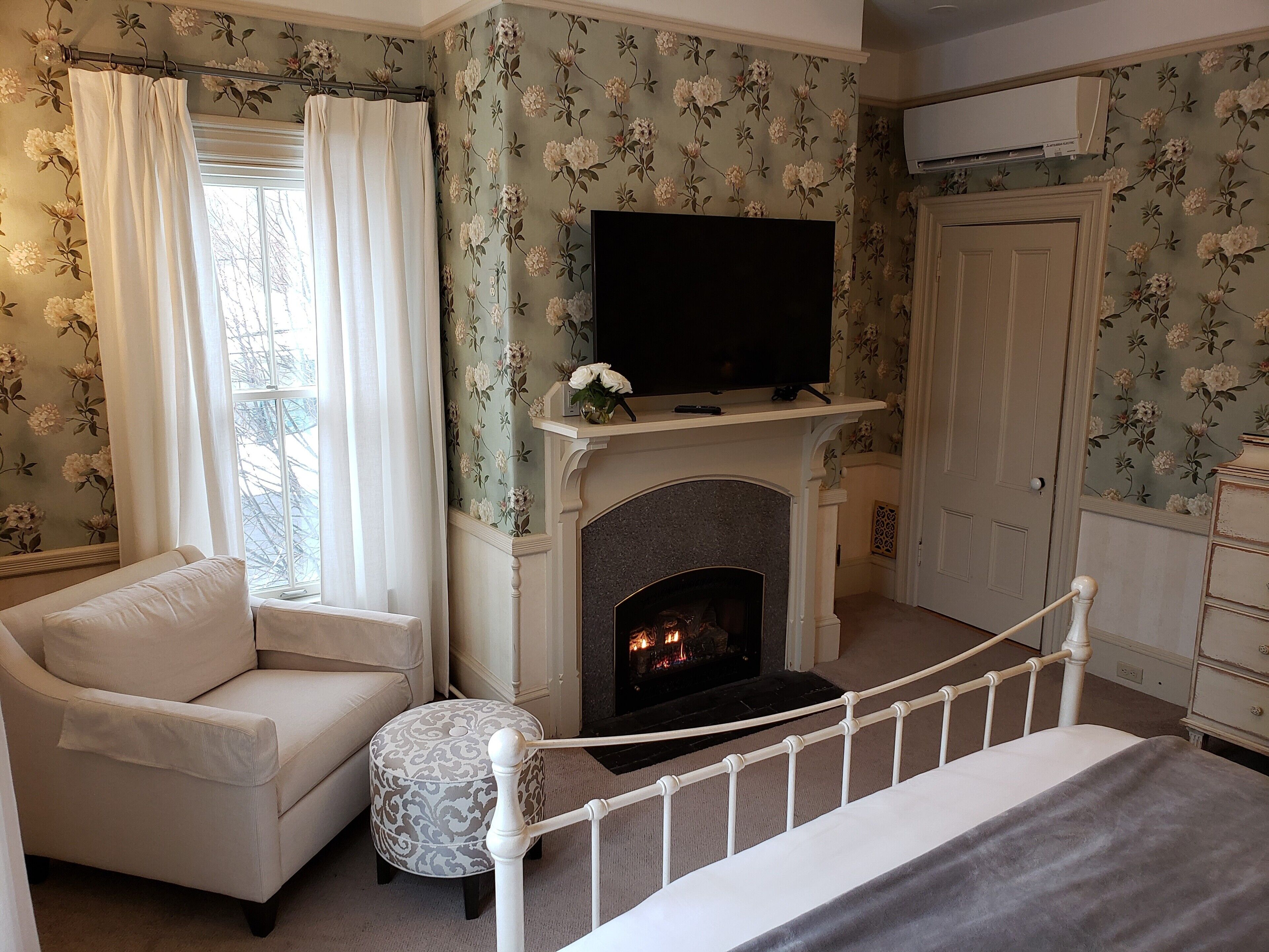 A bedroom with a fireplace, a television, a sofa, and a bed.