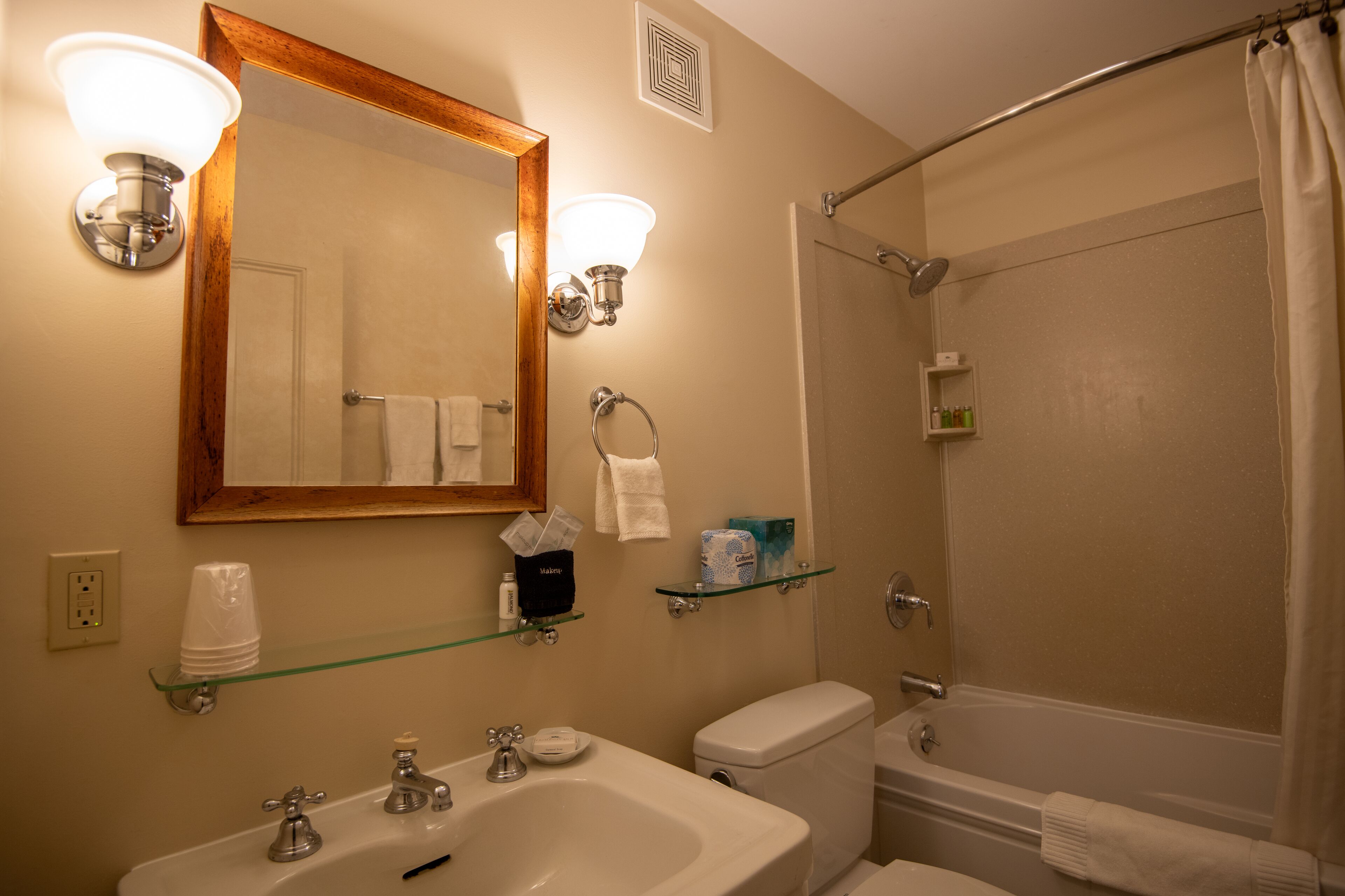A bathroom with a sink, mirror, and shower.