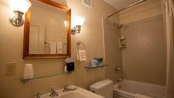 A bathroom with a sink, mirror, and shower.